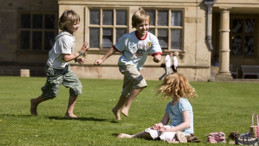 Children running in the garden at Hardwick Hall, Derbyshire, with the house behind